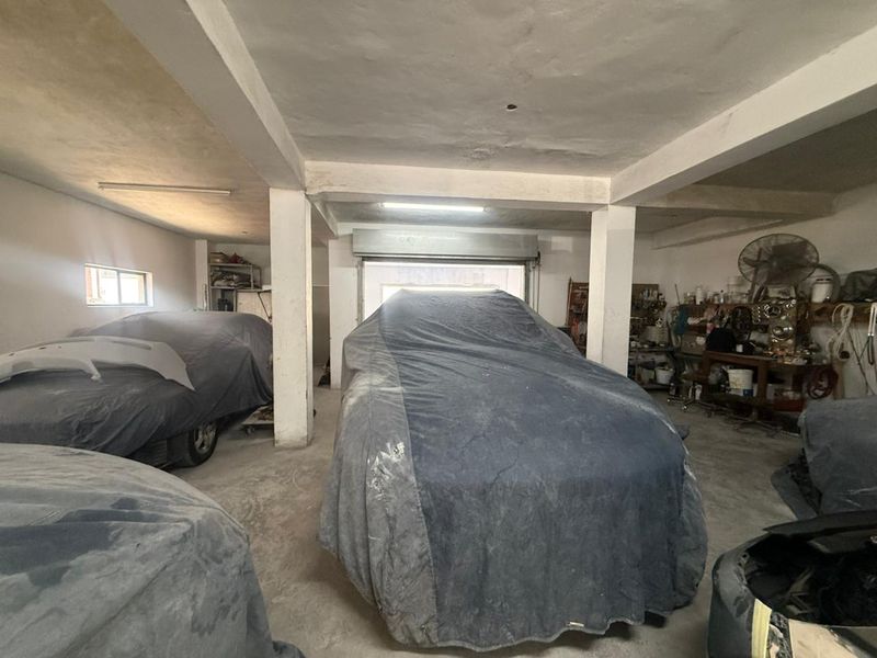 Spacious industrial garage area featuring concrete flooring, structural support columns, and a roller shutter door, suitable for workshop or storage use.