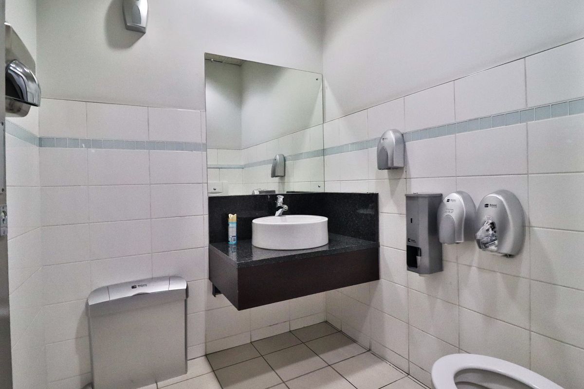 A clean, functional office restroom featuring a wall-mounted vanity with a vessel sink, granite countertop, and tiled finishes.