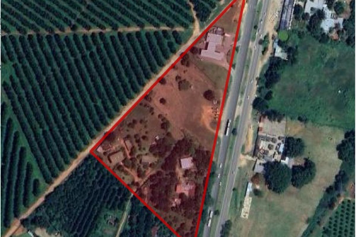 Aerial view of the small holding property showing the triangular plot layout, existing structures, and surrounding agricultural land adjacent to the main road.