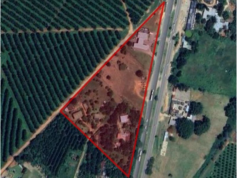 Aerial view of the small holding property showing the triangular plot layout, existing structures, and surrounding agricultural land adjacent to the main road.