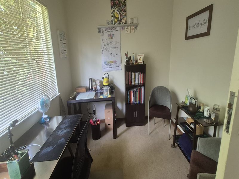 A functional office space featuring carpeted flooring and venetian blinds, providing a practical environment for work or study.