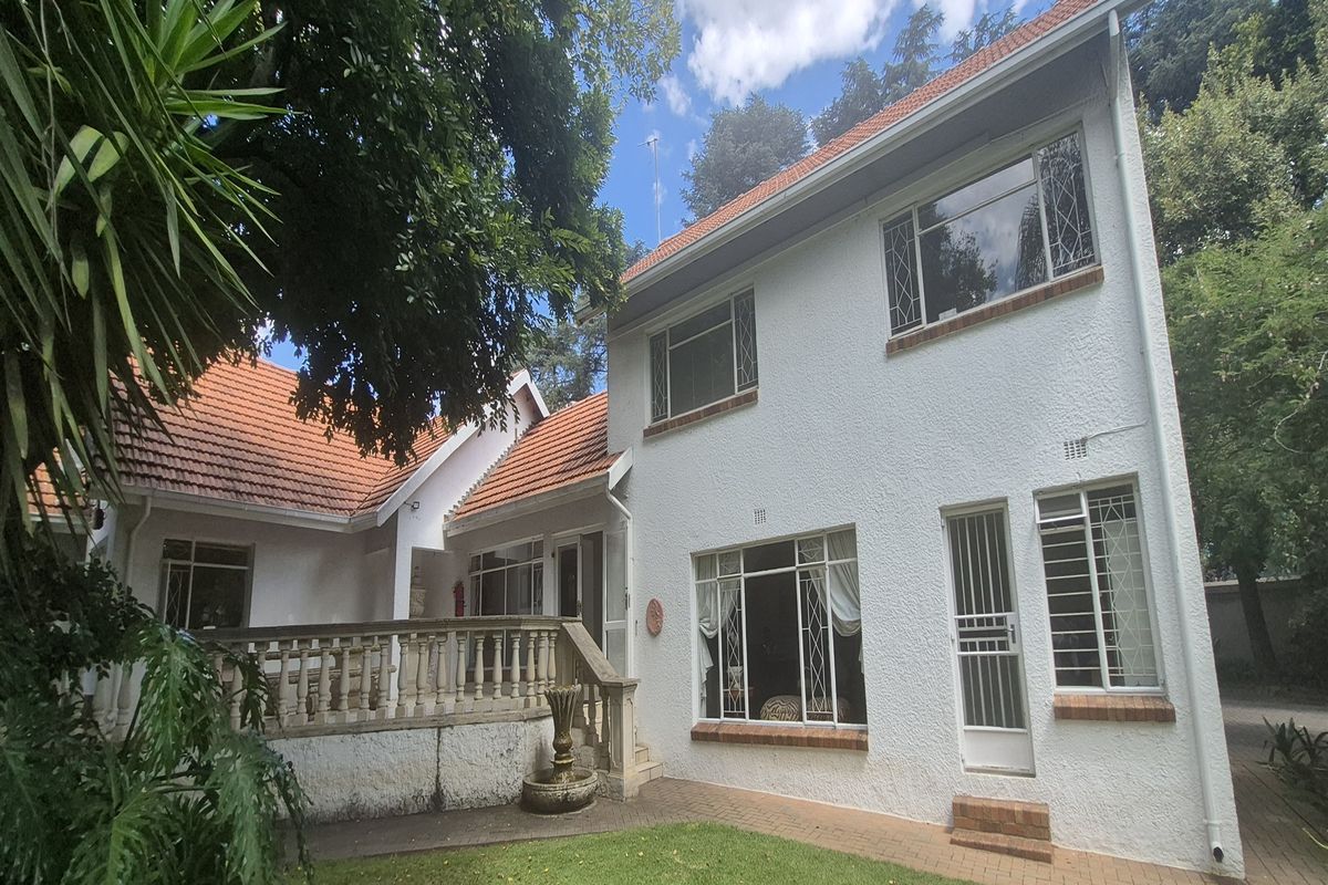 Rear view of the office property featuring a paved patio, balustrade, and white stucco facade with leaded glass windows.
