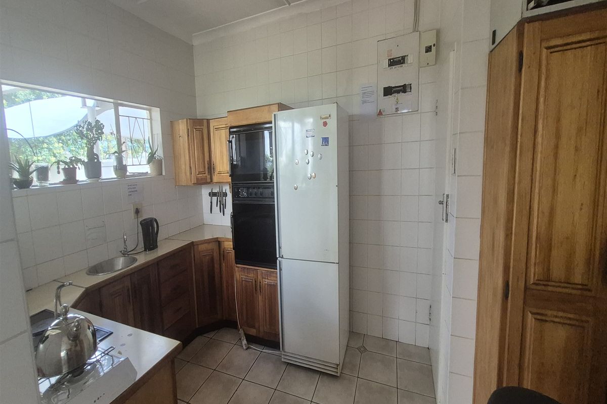 A functional kitchen featuring built-in wooden cabinetry, tiled surfaces, and a built-in oven, offering a practical workspace with potential for modern updates.