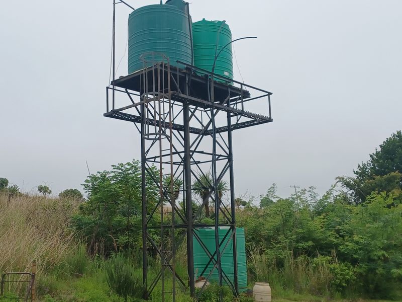 An elevated steel water storage tower featuring multiple plastic water tanks, providing essential water infrastructure for the farm property.