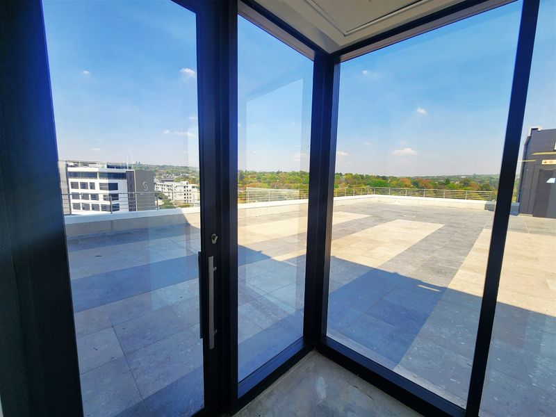 Spacious outdoor balcony featuring large format tiling, modern glass sliding doors, and a metal balustrade with expansive urban views.