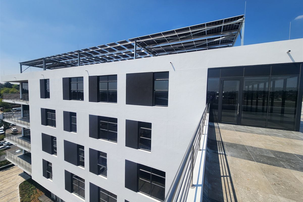 Modern office building exterior featuring a rooftop terrace with solar panels, glass doors, and contemporary architectural finishes.