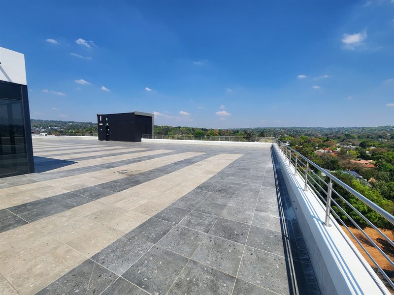 A spacious rooftop terrace featuring modern two-tone tiled flooring and a secure stainless steel balustrade with expansive panoramic views.