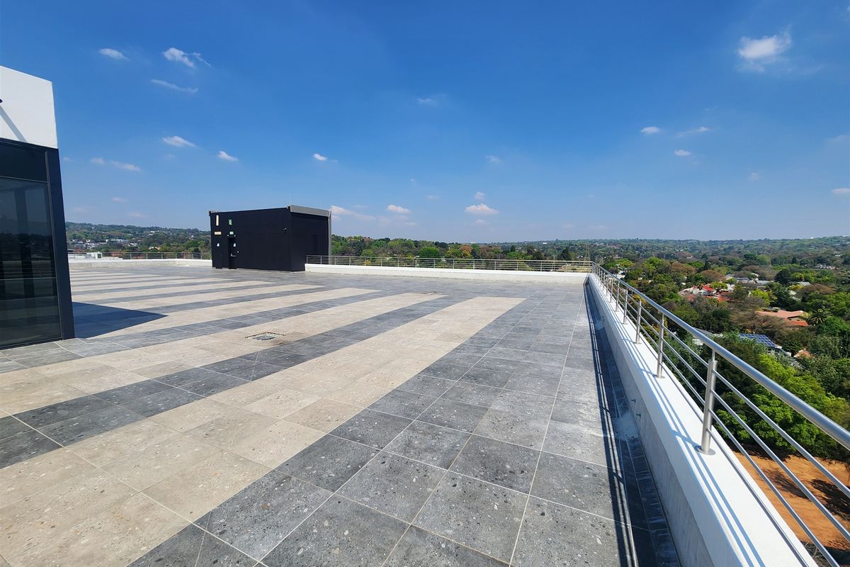 A spacious rooftop terrace featuring modern two-tone tiled flooring and a secure stainless steel balustrade with expansive panoramic views.