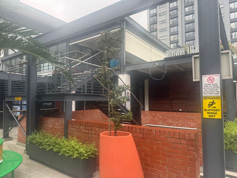 Exterior view of a modern retail building featuring a steel staircase, brick wall accents, and paved outdoor forecourt area.