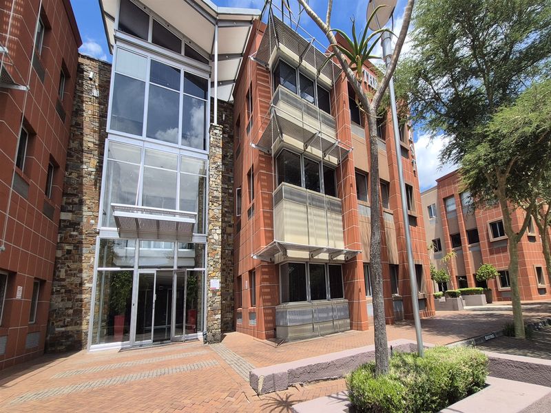 Modern office building exterior featuring a combination of brick, stone cladding, and large glass curtain wall sections with integrated metal sun shading.