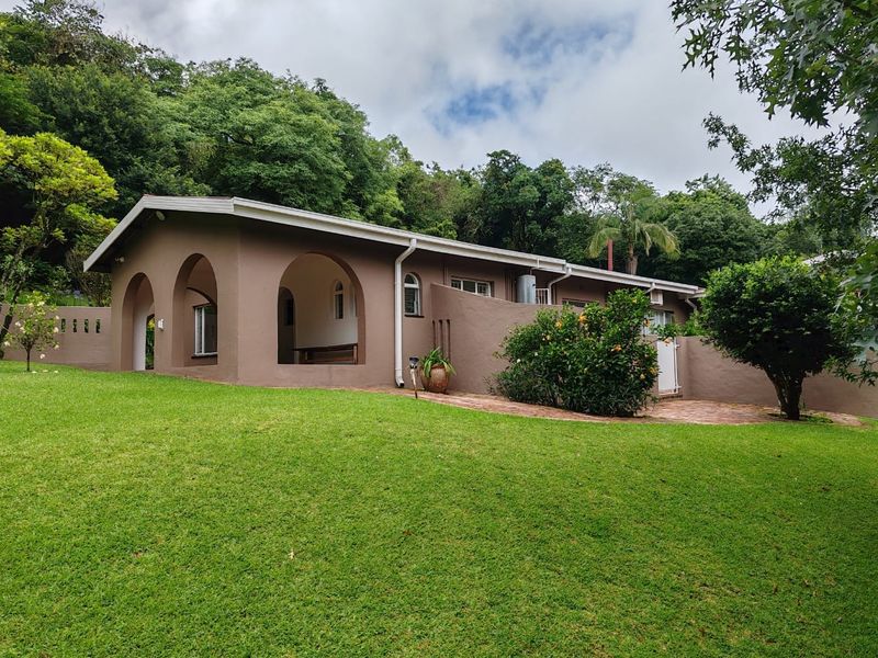 A view of the rear exterior of the farm property, featuring a covered patio with arched architectural details and a well-maintained lawn.
