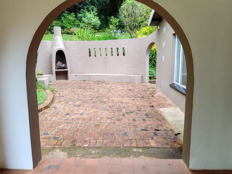 A charming outdoor patio area featuring a built-in masonry fireplace, brick paving, and a curved feature wall, perfect for outdoor entertaining.
