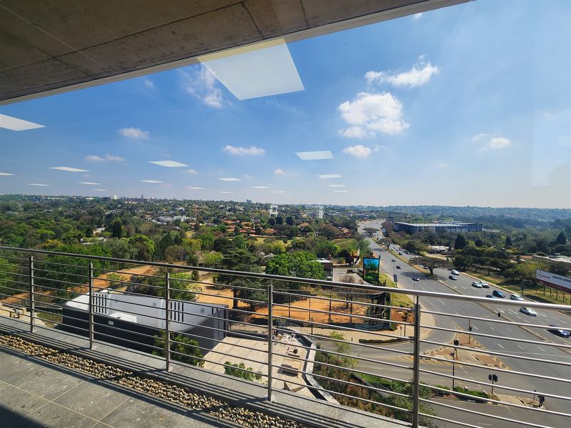 Elevated view from a modern office balcony overlooking the surrounding suburban landscape and main road infrastructure.