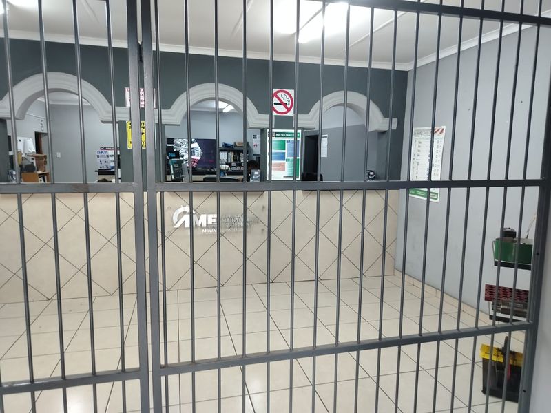Commercial reception area featuring a secure metal gate, tiled flooring, and a built-in service counter with decorative archway architectural details.