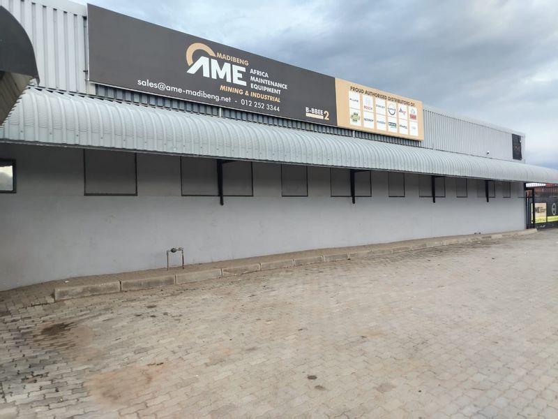 Front exterior view of a commercial industrial building featuring a paved driveway, metal awning, and prominent company signage.
