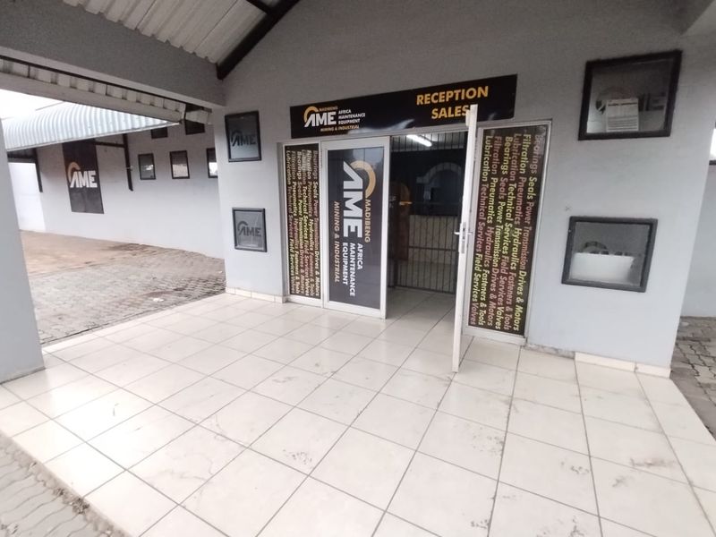 Commercial entrance area featuring tiled flooring, a covered porch, and prominent business signage for a maintenance and industrial equipment facility.