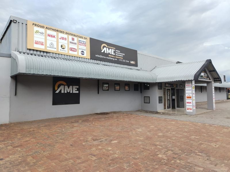 Front exterior view of a commercial industrial property featuring a paved driveway, corrugated metal roofing, and prominent company signage.