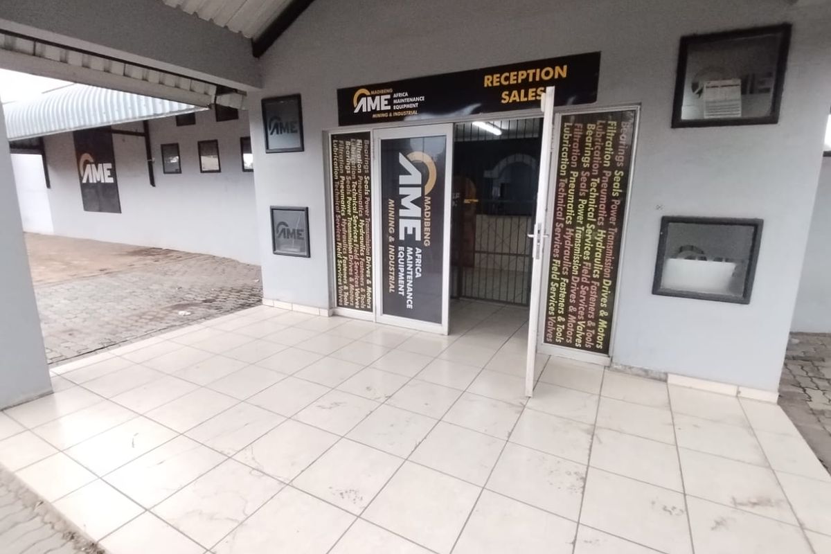 Commercial entrance area featuring tiled flooring, a covered porch, and prominent business signage for a maintenance and industrial equipment facility.
