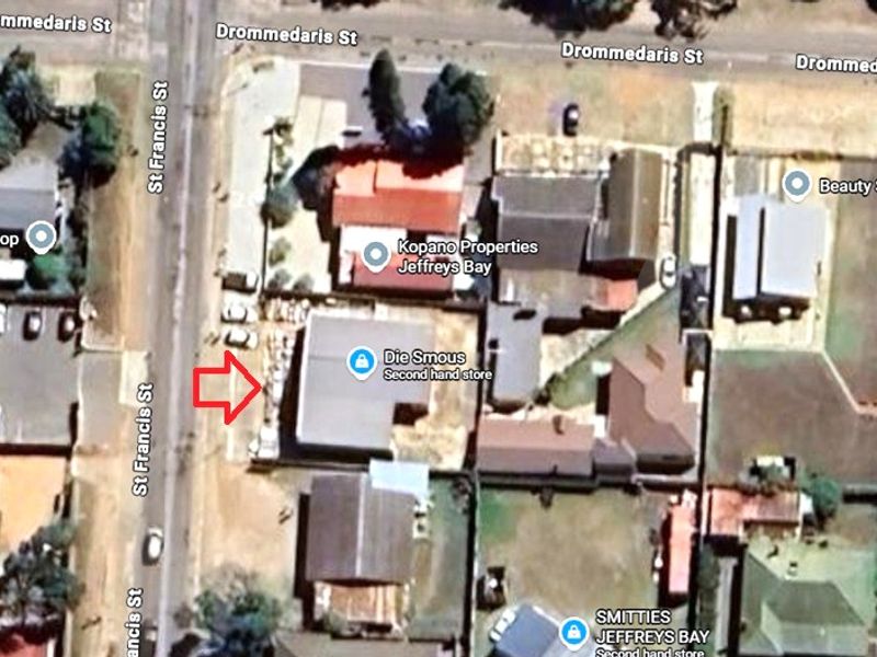 An aerial satellite view showing the property layout, roof structure, and surrounding street access in a commercial retail area.