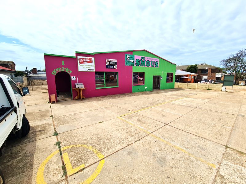 Front exterior view of a retail property featuring a paved parking area and a brightly painted masonry facade with commercial signage.
