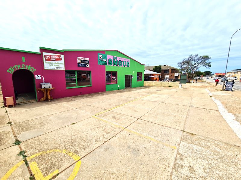 Front exterior view of a retail property featuring a paved parking area, prominent signage, and a distinctively painted masonry facade.