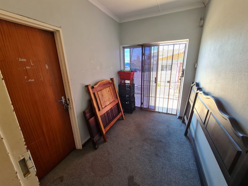An entry area featuring carpet flooring, a security gate, and a sliding door, currently vacant and ready for refurbishment.