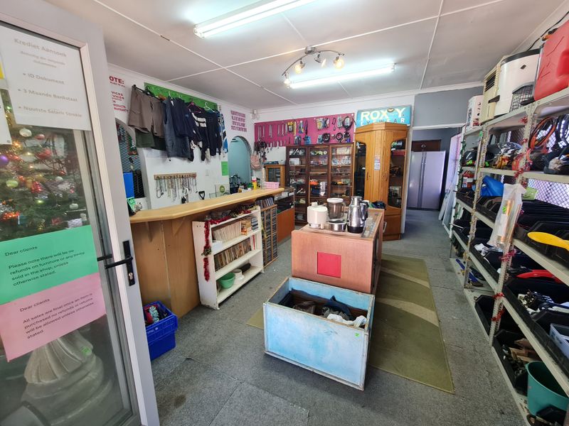 A retail utility and service area featuring a built-in counter, metal storage shelving, and glass display cabinetry, suitable for various commercial or retail operations.