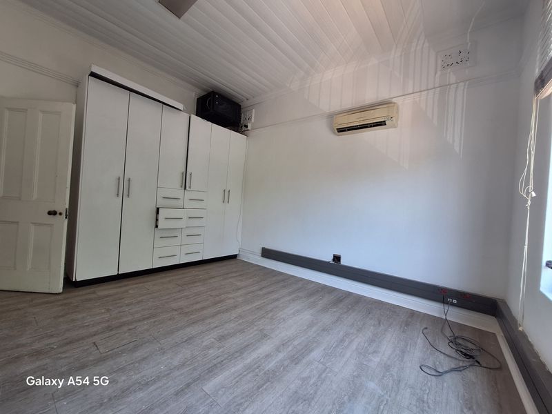 Office space featuring built-in storage cabinetry, wall-mounted air conditioning unit, and wood-look laminate flooring.