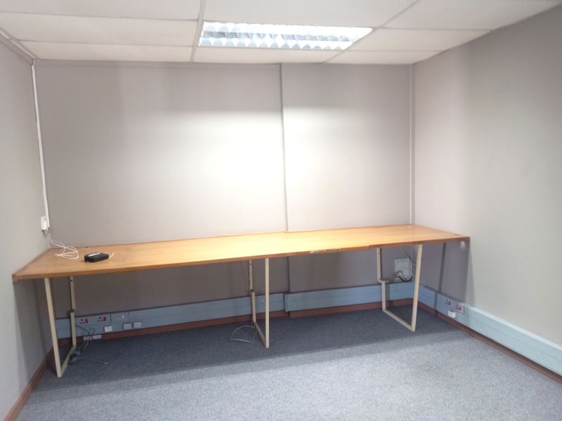A functional office space featuring a built-in desk, carpeted flooring, and recessed ceiling lighting, providing a practical environment for professional work.