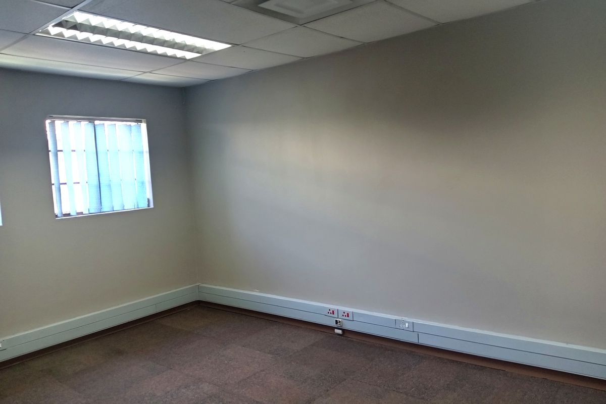 A vacant office space featuring a suspended ceiling with recessed lighting, vertical window blinds, and perimeter trunking for electrical and data connectivity.