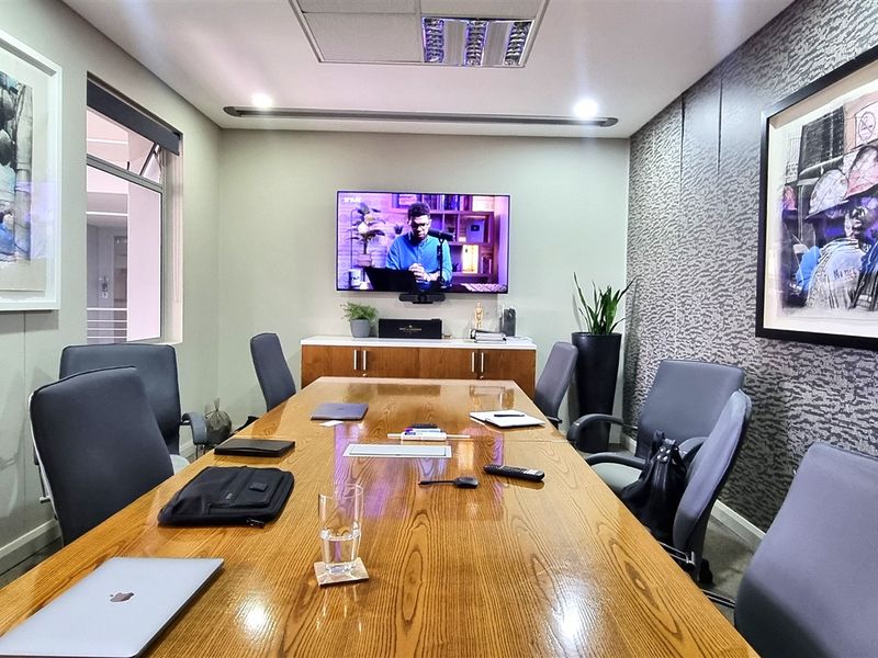 A professional boardroom featuring a large wooden conference table, integrated media display, and modern textured wall finishes.