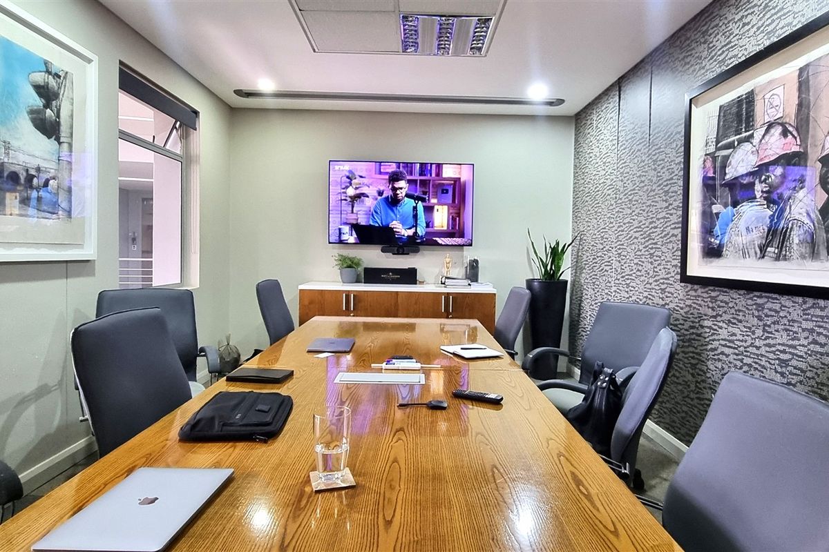 A professional boardroom featuring a large wooden conference table, integrated media display, and modern textured wall finishes.
