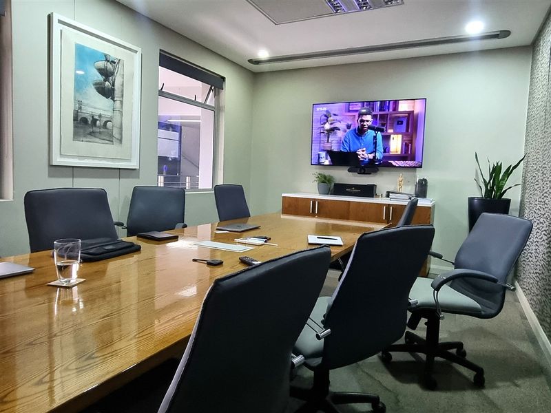 A professional boardroom featuring carpeted flooring, recessed ceiling lighting, and built-in cabinetry, providing a functional and well-maintained workspace environment.