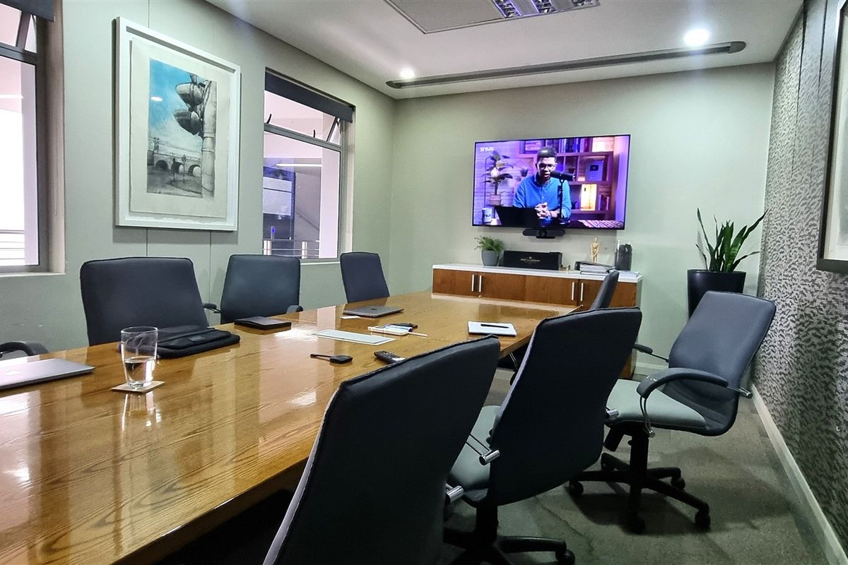 A professional boardroom featuring carpeted flooring, recessed ceiling lighting, and built-in cabinetry, providing a functional and well-maintained workspace environment.