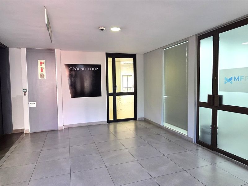 A clean and professional ground floor office entrance featuring tiled flooring, secure glass entry doors, and integrated access control systems.
