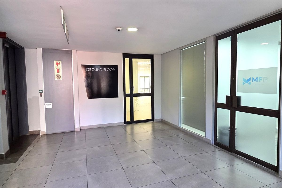 A clean and professional ground floor office entrance featuring tiled flooring, secure glass entry doors, and integrated access control systems.