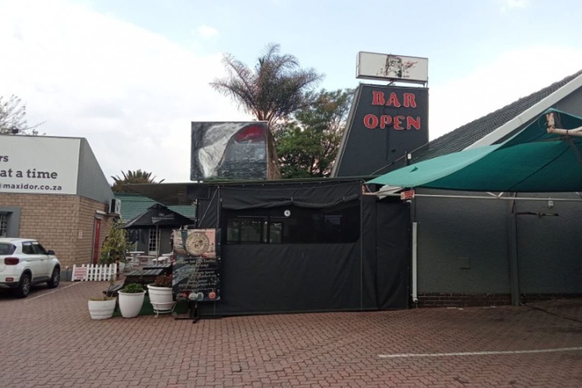 Exterior view of a commercial bar facility featuring paved parking area, signage, and covered outdoor space.