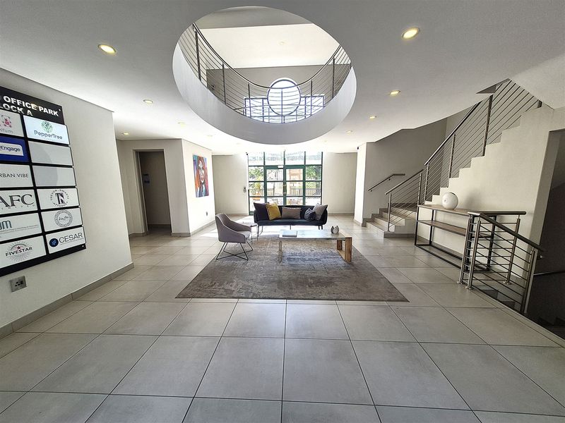 Spacious office park entrance lobby featuring a modern circular atrium, tiled flooring, and a prominent directory board for building tenants.
