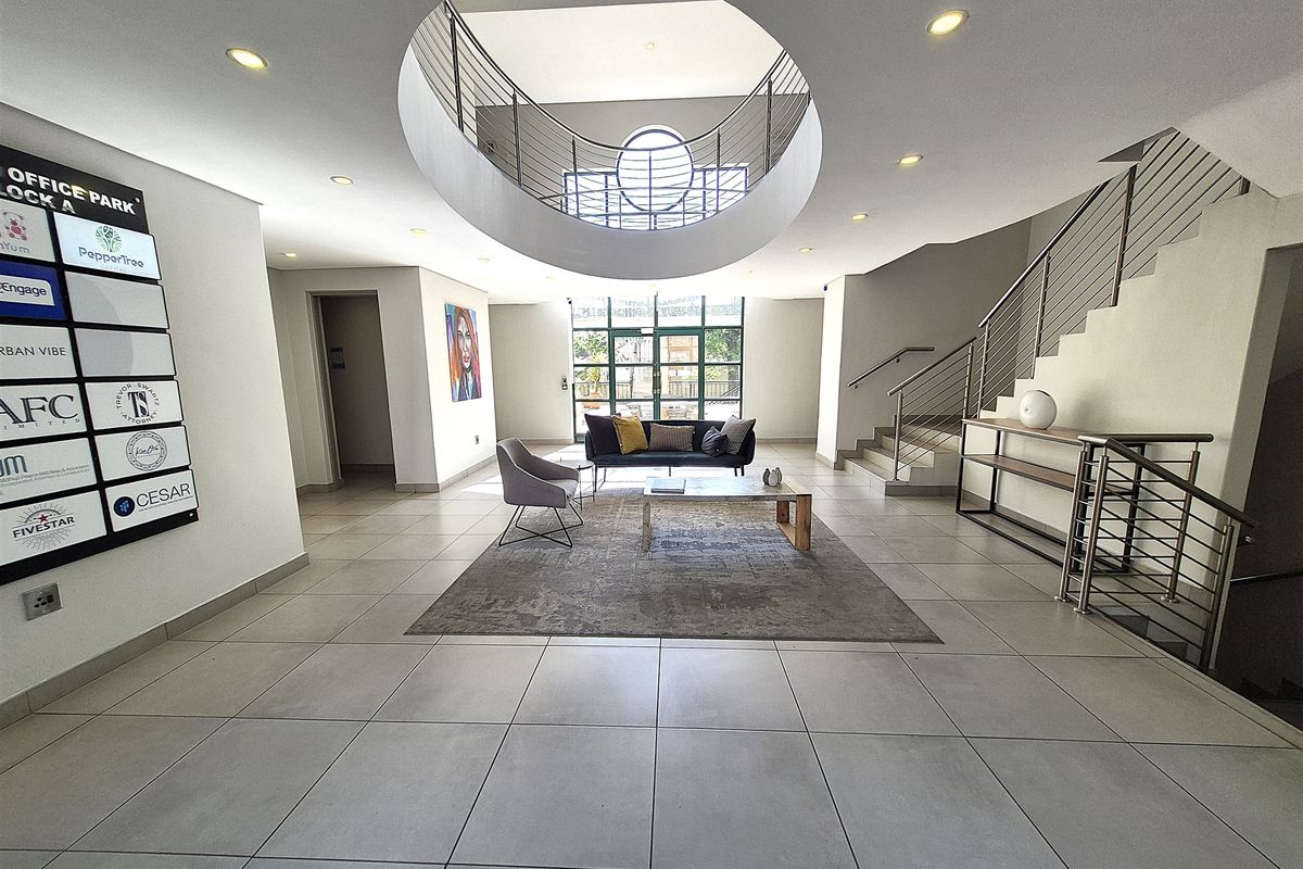 Spacious office park entrance lobby featuring a modern circular atrium, tiled flooring, and a prominent directory board for building tenants.
