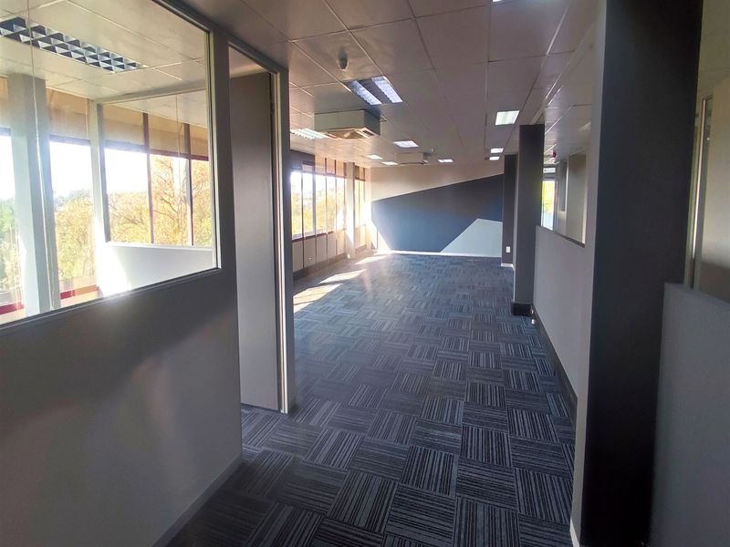 An open-plan office space featuring carpet tiles, suspended ceilings with recessed lighting, glass partitions, and integrated air conditioning.