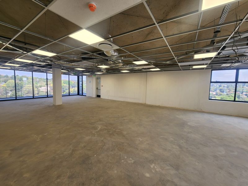 A spacious, open-plan office shell featuring large windows with scenic views, exposed concrete ceilings, and a flexible layout ready for custom fit-out.