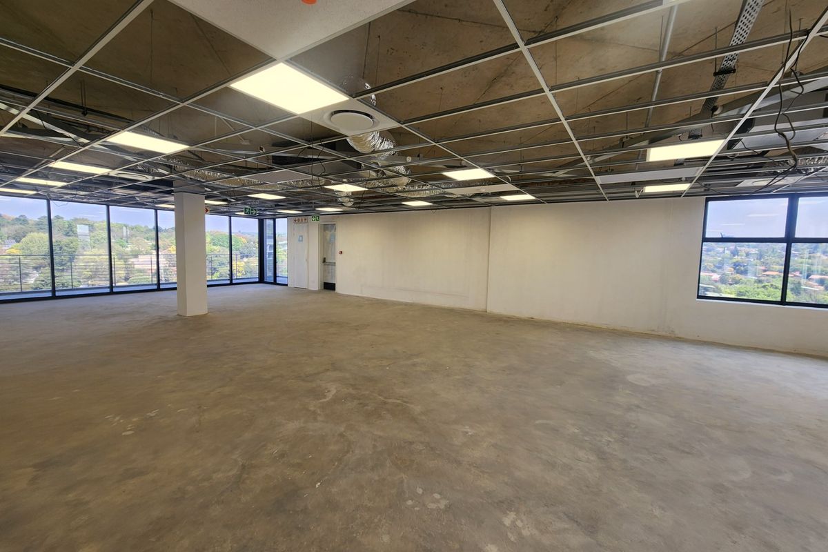 A spacious, open-plan office shell featuring large windows with scenic views, exposed concrete ceilings, and a flexible layout ready for custom fit-out.