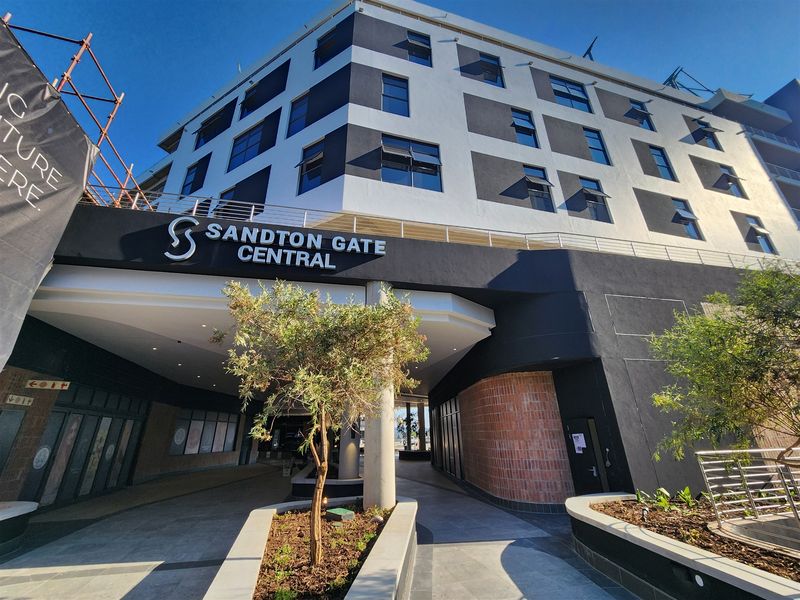 Modern commercial office building entrance at Sandton Gate Central, featuring contemporary architectural design, paved walkways, and integrated landscaping.