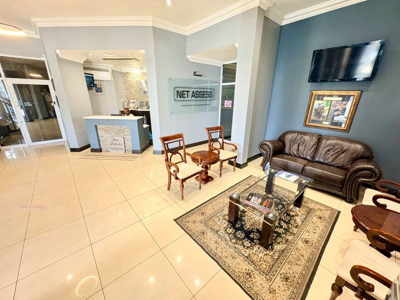 A professional office reception area featuring tiled flooring, a dedicated reception desk, and a comfortable waiting lounge with modern finishes.