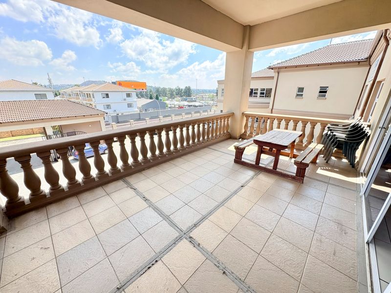 A spacious covered balcony featuring tiled flooring and a classic balustrade, offering an elevated outdoor area suitable for office break space.
