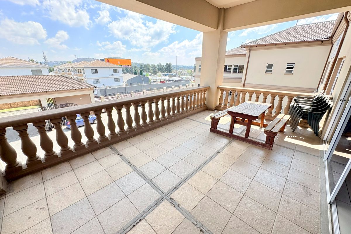 A spacious covered balcony featuring tiled flooring and a classic balustrade, offering an elevated outdoor area suitable for office break space.