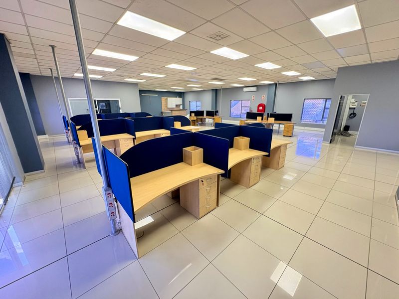 Spacious open-plan office area featuring tiled flooring, suspended ceilings with recessed lighting, and integrated air conditioning, providing a clean and professional workspace environment.