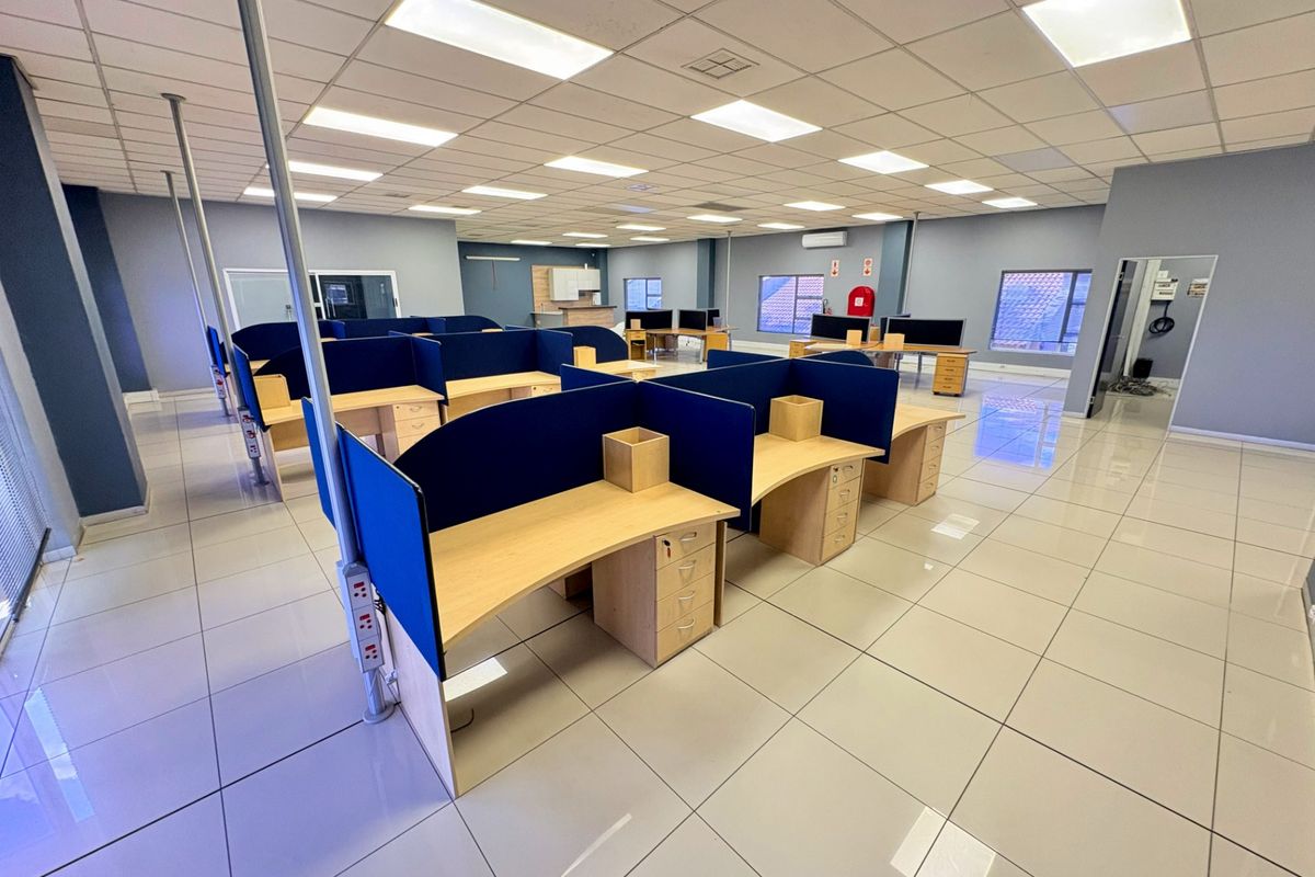 Spacious open-plan office area featuring tiled flooring, suspended ceilings with recessed lighting, and integrated air conditioning, providing a clean and professional workspace environment.