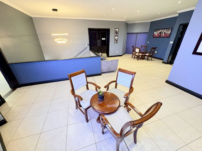 Spacious open-plan office area featuring tiled flooring, recessed downlighting, and a modern staircase railing, providing a versatile and well-maintained professional workspace.