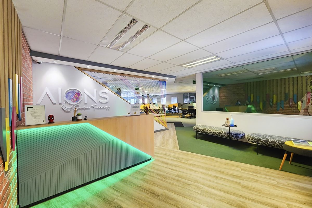 Modern office reception area featuring a custom desk with integrated lighting, exposed brick accents, and professional glass partitioning.